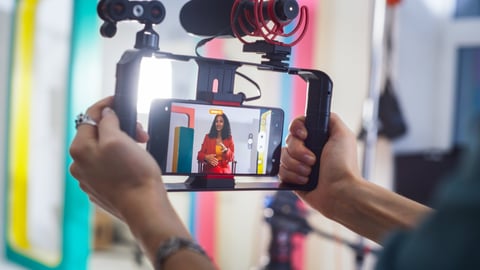 Young Female South Asian Host In Red Suite Engaging In Lively Discussion On Colorful Set